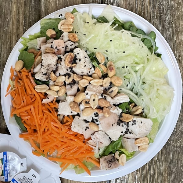 Woody's Famous Salads' Asian salad with chicken, shredded carrots, lettuce, peanuts, and sesame seeds.